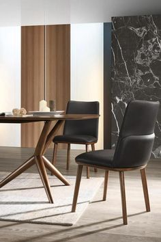 a dining table with two chairs and a marble wall in the background, along with an area rug on the floor