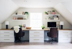 an attic office with two desks and shelves