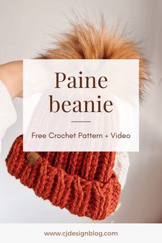 a woman's hand holding a red knitted hat with the words paine beanie on it