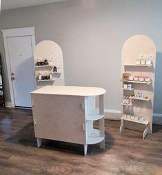 two shelving units in the middle of a room with wood floors and white walls