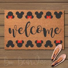 a welcome mat with minnie mouse ears and red bows on it next to ballet shoes