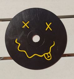 a black disk with yellow smiley faces painted on it's face and two crossed eyes