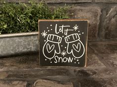 a sign that says let it snow in front of a potted plant