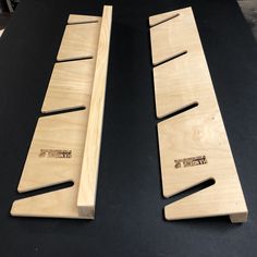 two pieces of wood sitting next to each other on a black counter top, one with holes in it