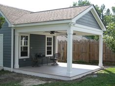 a small gray and white house with a covered patio