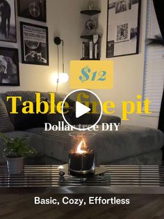 a table with a lit candle on top of it in front of a couch and pictures