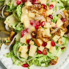 a white plate topped with lettuce and pomegranate covered in cheese