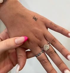 two hands with different designs on them and one has a small cross tattooed on the middle finger