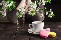 a woman sitting at a table next to a cup of coffee and macaroons