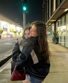 two girls standing on the sidewalk with their arms around each other