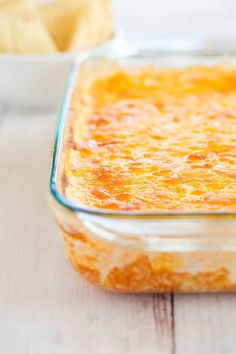 a casserole dish with cheese in it on a wooden table next to other dishes