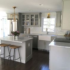 a kitchen with two stools in front of the sink and an island next to it