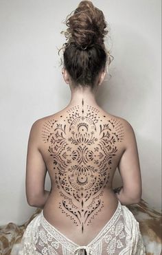 the back of a woman's body with tattoos on it