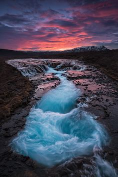 a river that has some water running down it with mountains in the backgroud