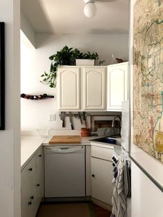 a map hangs on the wall in a kitchen with white cupboards and cabinets, along with a dishwasher