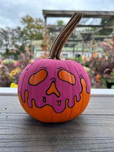 a painted pumpkin with an evil face on it's side sitting on a wooden table