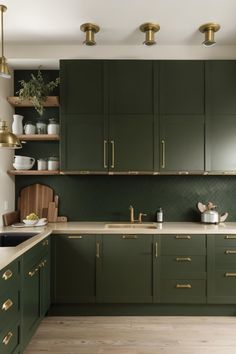 a kitchen with green cabinets and gold pulls on the cupboards is pictured in this image