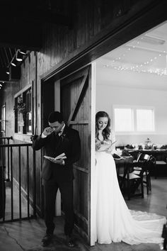 a man and woman standing in front of a wooden door with lights hanging from the ceiling