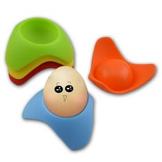 three different colored plastic toys with faces on them, including an egg and a spoon