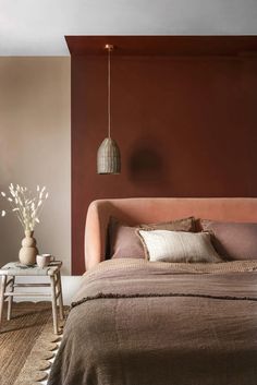 a bed sitting in a bedroom next to a table with a vase on top of it