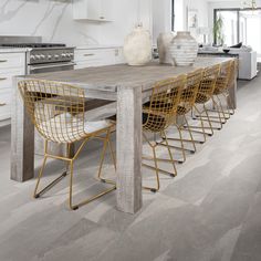 a dining room table with yellow chairs and white cabinets in front of the countertop