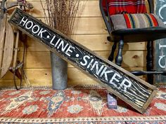 a wooden sign that says hook line sinker on it next to a chair and rug