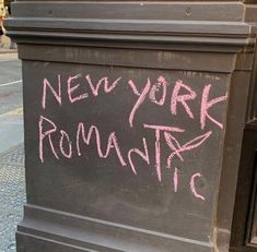 a chalkboard with the words new york romantics written on it next to a trash can