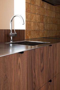 a kitchen sink sitting under a faucet next to a counter top with wooden cabinets