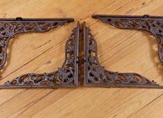 two ornate iron brackets sitting on top of a wooden floor