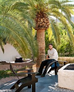 a man sitting on a bench under a palm tree