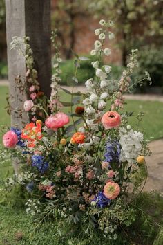 a bunch of flowers that are sitting on the ground in front of a wooden pole