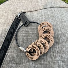 four personalized wooden necklaces on top of a gray pillow with black leather cord