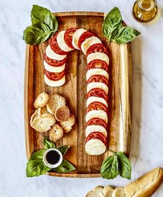 sliced tomatoes, mozzarella and basil on a wooden platter with garlic bread