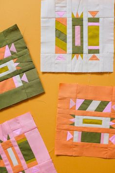 four different pieces of quilted fabric laid out on a yellow surface with scissors and thread