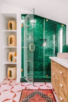 a bathroom with green tile and white walls, an open shower stall and shelving on the wall