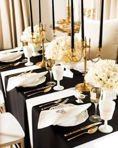 the table is set with black and white linens, gold place settings, and flowers