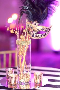 a tall vase filled with gold and black decorations on top of a striped table cloth