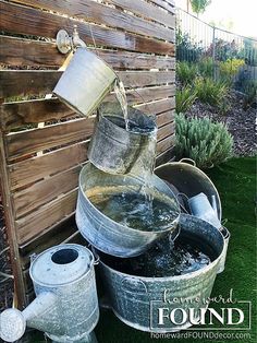 several buckets filled with water next to a wooden fence