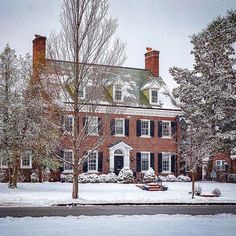 a large brick house with snow on the ground and trees in front of it,