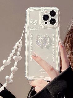 a woman holding up a cell phone case with pearls attached to the back of it