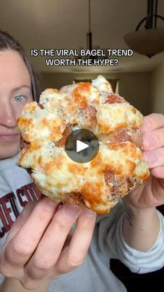 a woman holding up a piece of pizza in front of her face with the caption is the virtual bagel trend worth the hyppe?