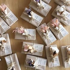 many wrapped gift boxes on a table with ribbons and tags tied around the top one