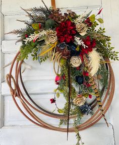 a wreath with flowers and feathers hanging on a door