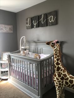 a giraffe standing next to a baby's crib in a bedroom