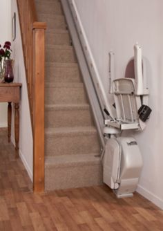 a stair lift is attached to the wall next to a wooden table with flowers on it