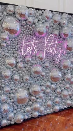 a party sign made out of balloons on top of a wooden floor with the words let's party written above it