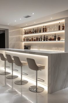 an elegant bar with stools and bottles on the wall behind it in a white room