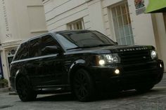 a black range rover parked on the side of a street in front of a building