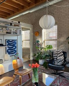 a living room filled with furniture and lots of windows next to a book shelf on top of a hard wood floor