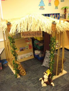 a classroom with a tiki hut made out of wood and grass on the floor